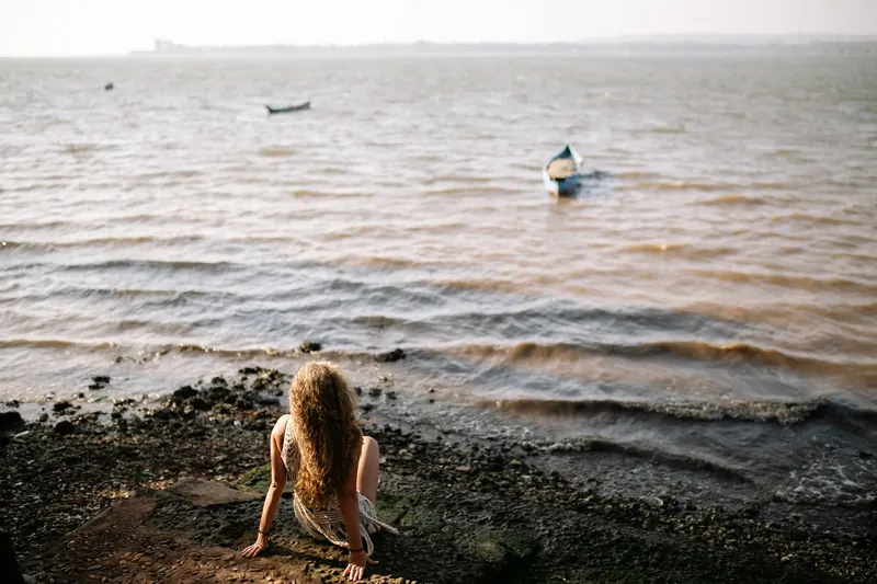 Une femme assise sur le sable face à la mer